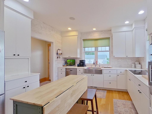 6828 Rhoades Ave SW, Cokato, MN 55321 - kitchen with decorative backsplash, light countertops, stainless steel dishwasher, light wood-style flooring, and black electric stovetop