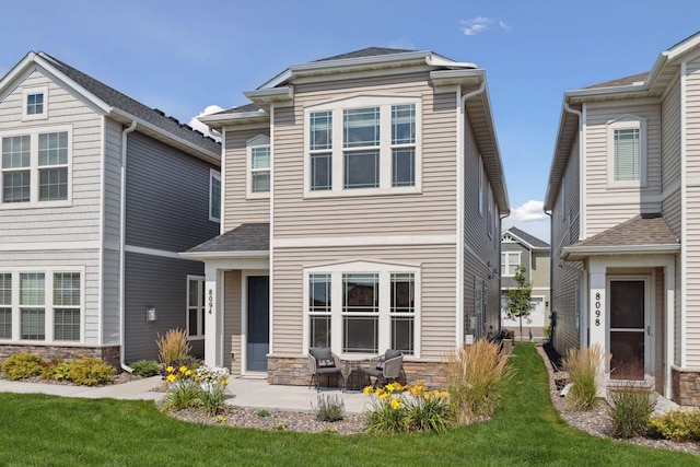 8094 Arrowwood Ln N, Maple Grove, MN 55369 - view of front facade featuring stone siding, a patio, and a front lawn