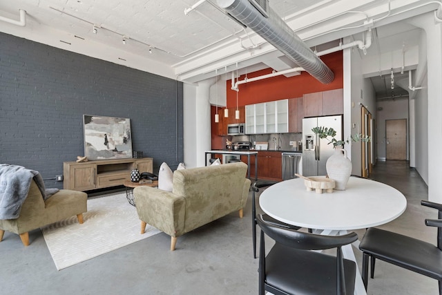2929 Chicago Ave Unit 1208, Minneapolis, MN 55407 - living room featuring a high ceiling, finished concrete floors, brick wall, and track lighting