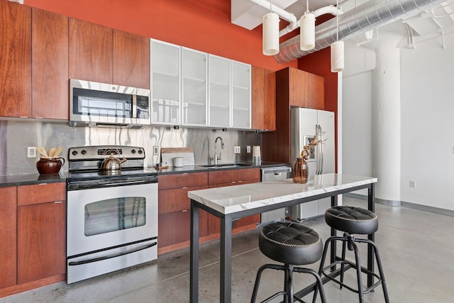 2929 Chicago Ave Unit 1208, Minneapolis, MN 55407 - kitchen featuring appliances with stainless steel finishes, brown cabinetry, concrete floors, decorative backsplash, and a high ceiling