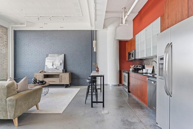 2929 Chicago Ave Unit 1208, Minneapolis, MN 55407 - kitchen with stainless steel appliances, brick wall, rail lighting, finished concrete floors, and white cabinets