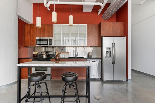 2929 Chicago Ave Unit 1208, Minneapolis, MN 55407 - kitchen with appliances with stainless steel finishes, brown cabinets, concrete floors, hanging light fixtures, and a center island