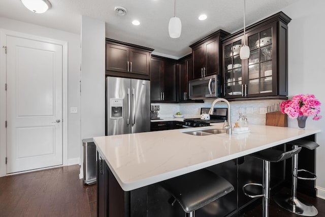 8312 Jonquil Ln N, Maple Grove, MN 55369 - kitchen with stainless steel appliances, a peninsula, dark brown cabinetry, glass insert cabinets, and dark wood-type flooring