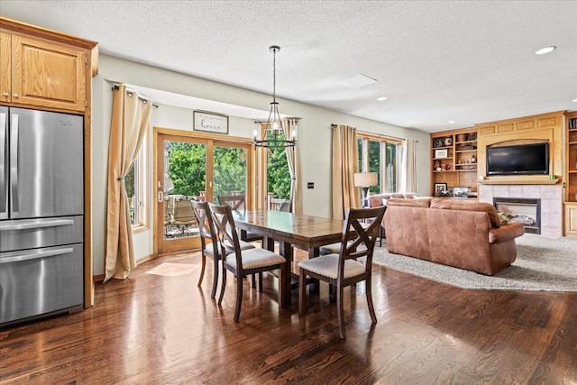 1111 Woods Creek Dr, Delano, MN 55328 - dining space featuring a textured ceiling, a tiled fireplace, dark wood-style flooring, a chandelier, and built in shelves