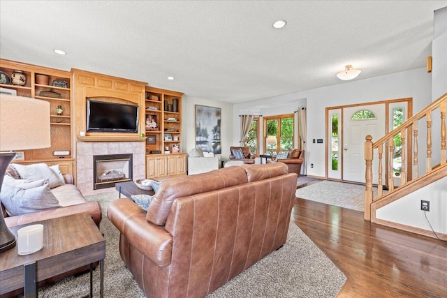 1111 Woods Creek Dr, Delano, MN 55328 - living area featuring a textured ceiling, wood finished floors, a tiled fireplace, recessed lighting, and stairs