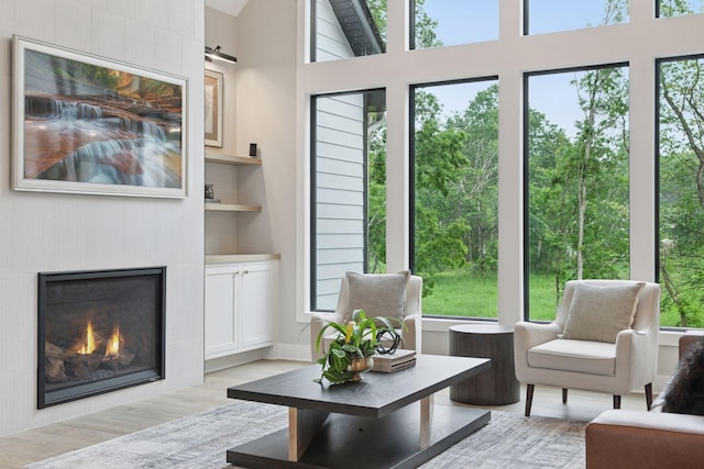 4864 148th Ave, Ham Lake, MN 55304 - living area featuring light wood-style flooring, a tiled fireplace, built in features, and a high ceiling