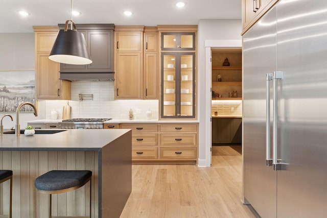 4864 148th Ave, Ham Lake, MN 55304 - kitchen with stainless steel built in refrigerator, light wood finished floors, a kitchen breakfast bar, glass insert cabinets, and recessed lighting