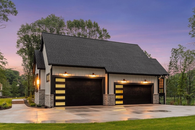 4864 148th Ave, Ham Lake, MN 55304 - view of front facade featuring stone siding, driveway, board and batten siding, a garage, and a shingled roof