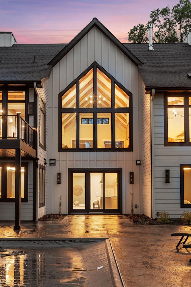 4864 148th Ave, Ham Lake, MN 55304 - back of house at dusk featuring board and batten siding, a shingled roof, and a balcony