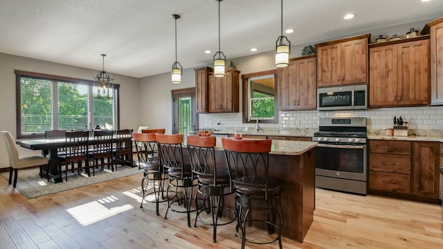 30488 292nd St, Lake Holcombe Twp, WI 54745 - kitchen featuring appliances with stainless steel finishes, light wood-style flooring, a breakfast bar, a kitchen island, and decorative backsplash
