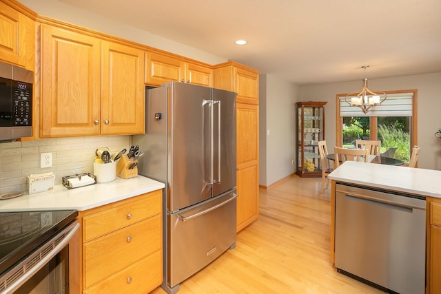5209 Goodview Ln NW, Rochester, MN 55901 - kitchen with stainless steel appliances, a chandelier, light wood-style floors, decorative backsplash, and light countertops