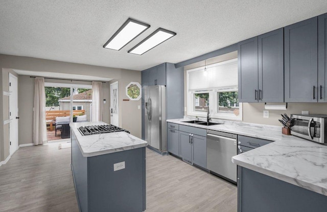 402 Clifton St, Saint Paul, MN 55102 - kitchen featuring appliances with stainless steel finishes, a kitchen island, light wood-type flooring, light stone countertops, and a textured ceiling