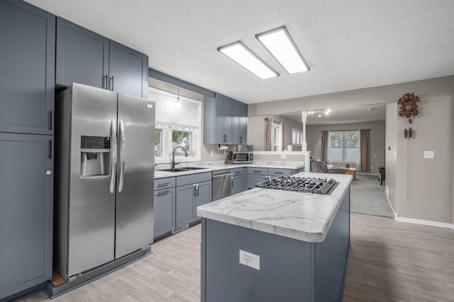 402 Clifton St, Saint Paul, MN 55102 - kitchen featuring stainless steel appliances, light wood finished floors, plenty of natural light, a center island, and a textured ceiling