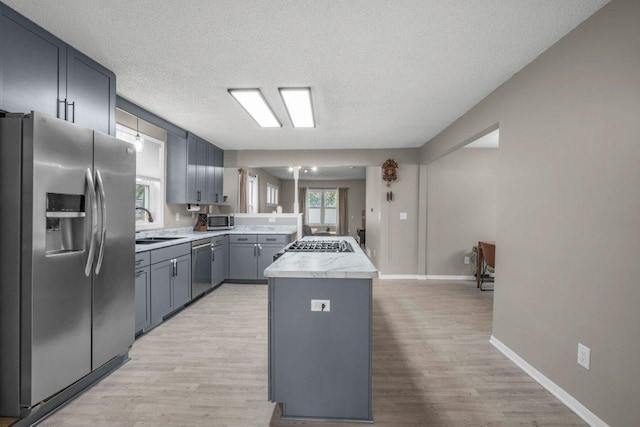 402 Clifton St, Saint Paul, MN 55102 - kitchen with stainless steel appliances, light countertops, a textured ceiling, light wood-style flooring, and a peninsula