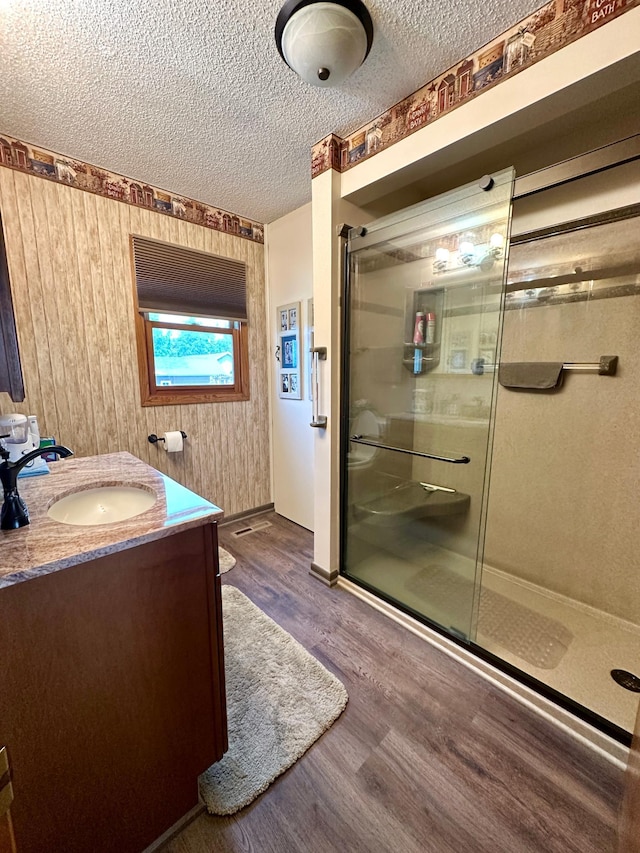 607 Washington Ave, Spring Valley, MN 55975 - bathroom with a stall shower, vanity, wood finished floors, and a textured ceiling