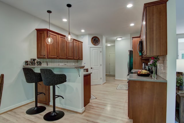 1403 Elm Ave W, Menomonie, WI 54751 - kitchen with a breakfast bar area, light wood-style flooring, a peninsula, tasteful backsplash, and recessed lighting