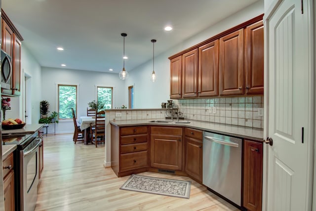 1403 Elm Ave W, Menomonie, WI 54751 - kitchen with appliances with stainless steel finishes, light wood-style flooring, decorative backsplash, a peninsula, and pendant lighting