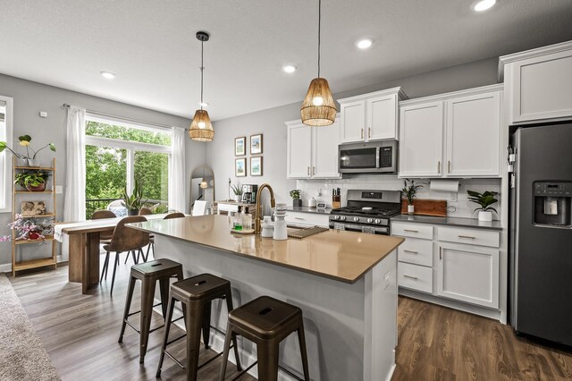 1771 Emerson Ct, Chaska, MN 55318 - kitchen with appliances with stainless steel finishes, recessed lighting, white cabinets, a breakfast bar, and tasteful backsplash