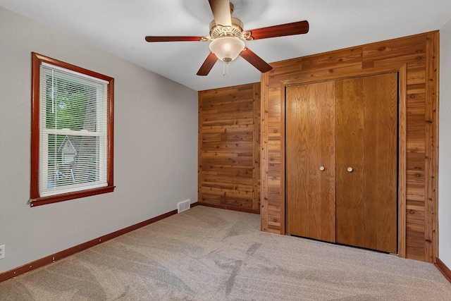 920 2nd Ave S, Sauk Rapids, MN 56379 - unfurnished bedroom with carpet floors, wood walls, a closet, and a ceiling fan