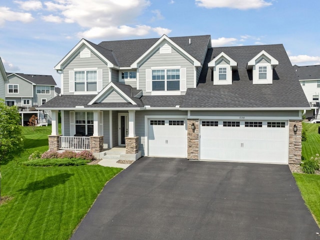 7154 Alphabet St, Chanhassen, MN 55317 - view of front of property featuring covered porch, asphalt driveway, stone siding, and a front lawn