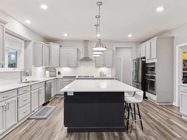 7154 Alphabet St, Chanhassen, MN 55317 - kitchen featuring wall chimney exhaust hood, stainless steel appliances, a kitchen island, light wood-type flooring, and a kitchen bar
