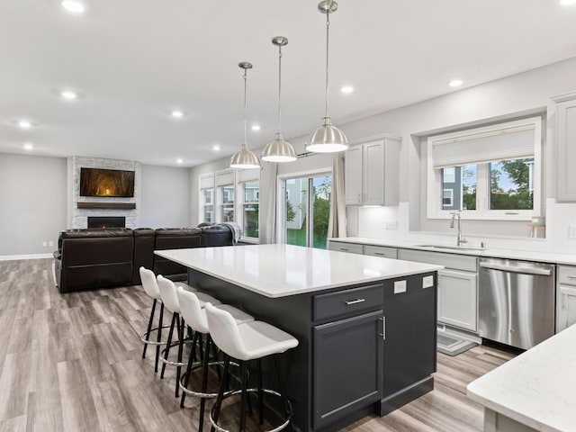 7154 Alphabet St, Chanhassen, MN 55317 - kitchen featuring dishwasher, light countertops, light wood-style flooring, a kitchen island, and plenty of natural light