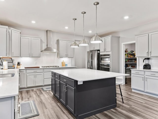7154 Alphabet St, Chanhassen, MN 55317 - kitchen featuring appliances with stainless steel finishes, wall chimney exhaust hood, tasteful backsplash, light wood-style floors, and a kitchen island