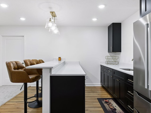 7154 Alphabet St, Chanhassen, MN 55317 - kitchen featuring stainless steel refrigerator, a breakfast bar, dark cabinetry, light countertops, and a peninsula