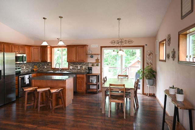 11764 35th Ave SE, Becker, MN 55308 - kitchen featuring appliances with stainless steel finishes, vaulted ceiling, tasteful backsplash, dark countertops, and brown cabinetry