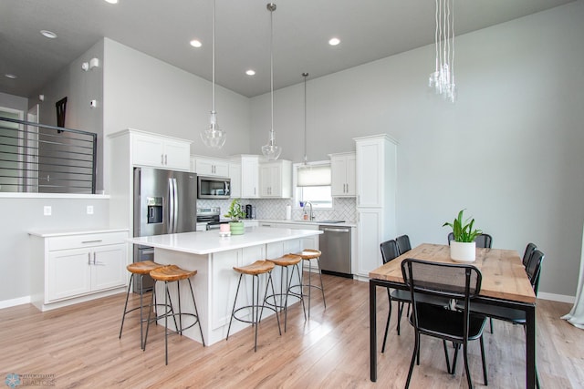 5252 8th Ct W, West Fargo, ND 58078 - kitchen featuring stainless steel appliances, a center island, a breakfast bar area, light wood finished floors, and a high ceiling