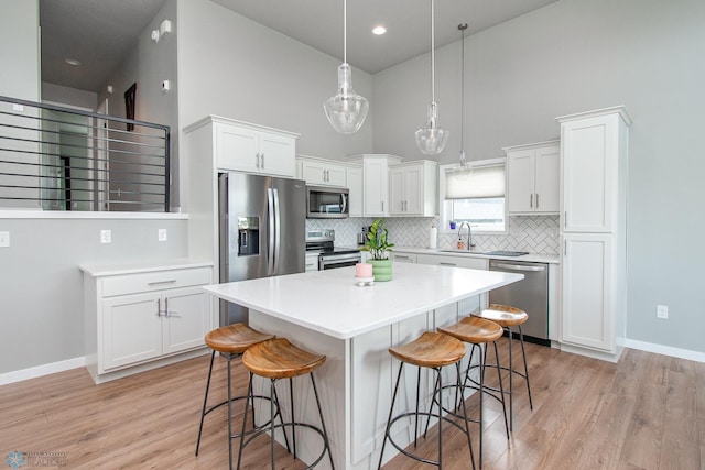 5252 8th Ct W, West Fargo, ND 58078 - kitchen with appliances with stainless steel finishes, a high ceiling, white cabinetry, a breakfast bar area, and backsplash