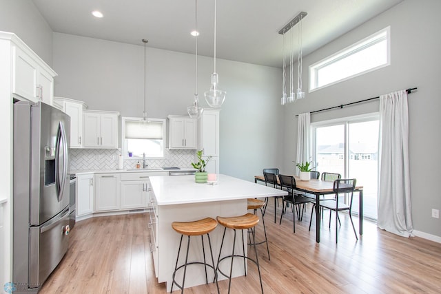 5252 8th Ct W, West Fargo, ND 58078 - kitchen featuring stainless steel fridge with ice dispenser, a towering ceiling, a center island, a breakfast bar area, and white cabinetry