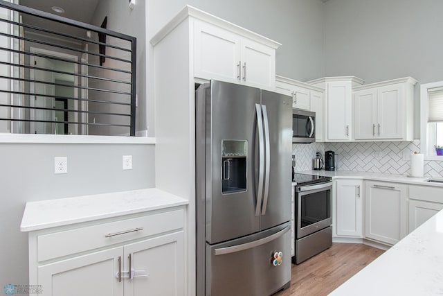 5252 8th Ct W, West Fargo, ND 58078 - kitchen with stainless steel appliances, decorative backsplash, white cabinetry, and light wood finished floors