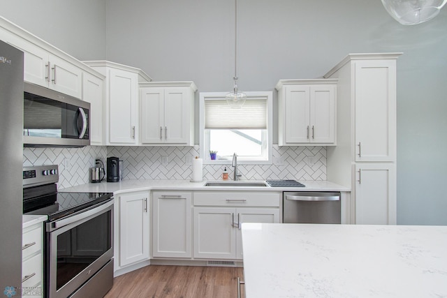 5252 8th Ct W, West Fargo, ND 58078 - kitchen with stainless steel appliances, backsplash, white cabinets, hanging light fixtures, and light wood-style floors