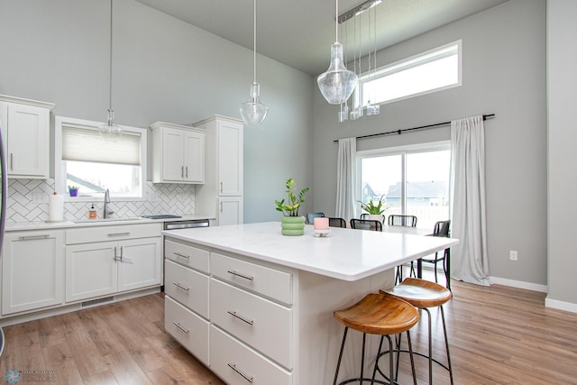 5252 8th Ct W, West Fargo, ND 58078 - kitchen featuring a towering ceiling, a center island, a kitchen breakfast bar, tasteful backsplash, and white cabinetry