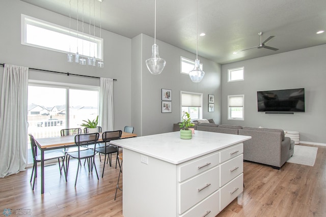 5252 8th Ct W, West Fargo, ND 58078 - kitchen with a towering ceiling, light wood finished floors, white cabinets, a ceiling fan, and a center island