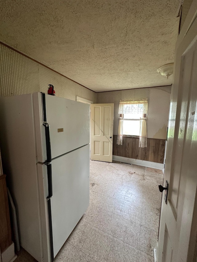 613 Cedar St, Luverne, MN 56156 - kitchen with freestanding refrigerator, tile patterned floors, a textured ceiling, and wooden walls