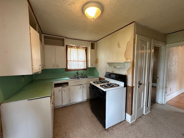 613 Cedar St, Luverne, MN 56156 - kitchen with white range with gas cooktop, light flooring, a textured ceiling, white cabinets, and light countertops