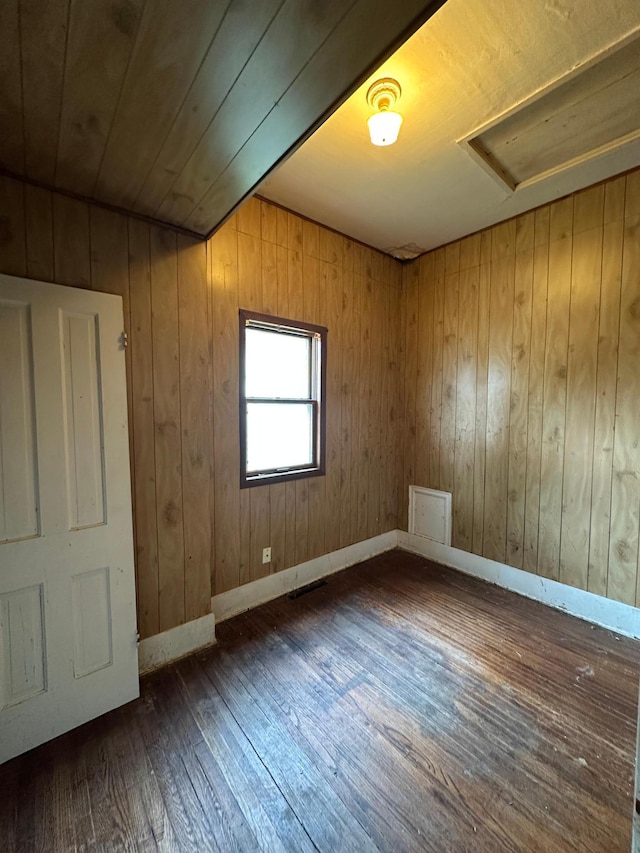 613 Cedar St, Luverne, MN 56156 - spare room featuring dark wood-type flooring, attic access, and wooden walls