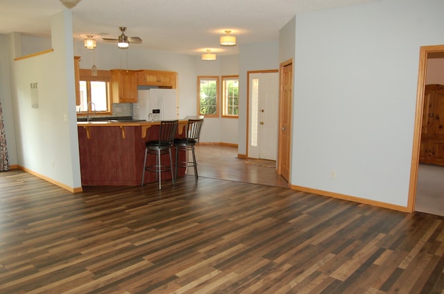 224 Goldfinch Ln, Clearwater, MN 55320 - kitchen with white refrigerator with ice dispenser, a peninsula, dark wood finished floors, a breakfast bar area, and ceiling fan