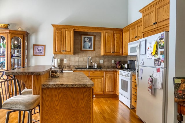 5010 384th Trl, North Branch, MN 55056 - kitchen with white appliances, a kitchen bar, dark countertops, light wood finished floors, and tasteful backsplash
