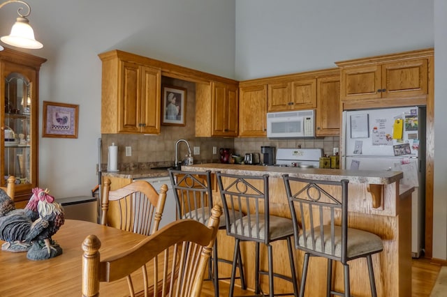 5010 384th Trl, North Branch, MN 55056 - kitchen with white appliances, decorative backsplash, a kitchen bar, and brown cabinets