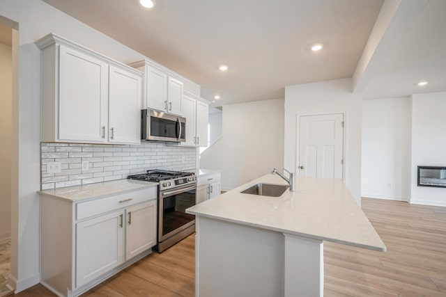10280 187th Ave NW, Elk River, MN 55330 - kitchen featuring appliances with stainless steel finishes, tasteful backsplash, light wood-style flooring, a center island with sink, and recessed lighting