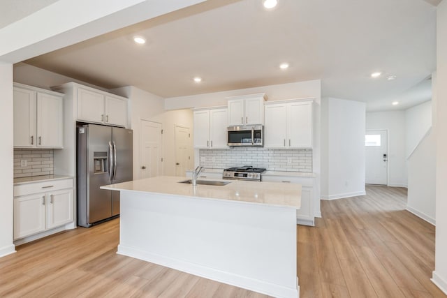 10280 187th Ave NW, Elk River, MN 55330 - kitchen with stainless steel appliances, backsplash, a kitchen island with sink, white cabinetry, and light countertops