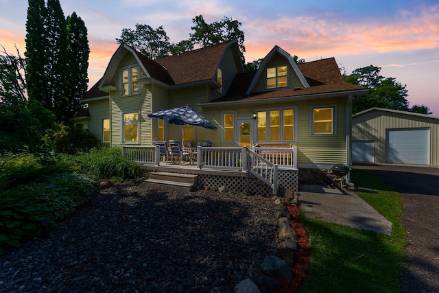 11826 State Road 48, Frederic, WI 54837 - back of house at dusk featuring an outbuilding, a detached garage, asphalt driveway, and a wooden deck