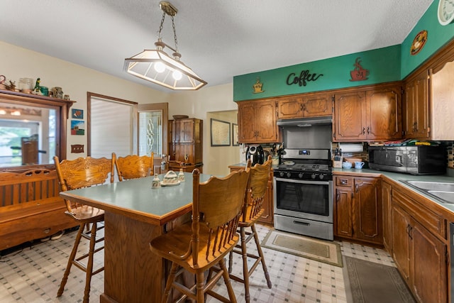 11826 State Road 48, Frederic, WI 54837 - kitchen with appliances with stainless steel finishes, under cabinet range hood, light floors, a kitchen breakfast bar, and a textured ceiling