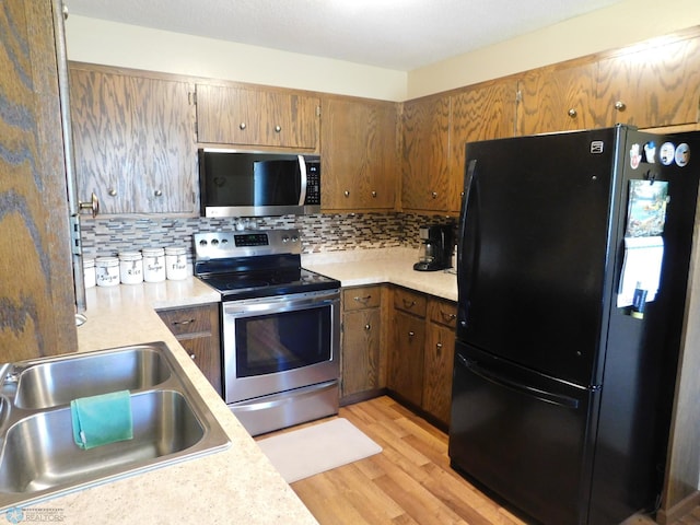 961 4th Ave W Unit B, West Fargo, ND 58078 - kitchen featuring appliances with stainless steel finishes, light countertops, light wood-style flooring, and backsplash