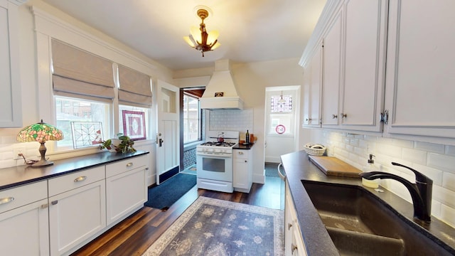 315 Fountain St, Albert Lea, MN 56007 - kitchen featuring white gas range, premium range hood, dark countertops, tasteful backsplash, and dark wood-style floors