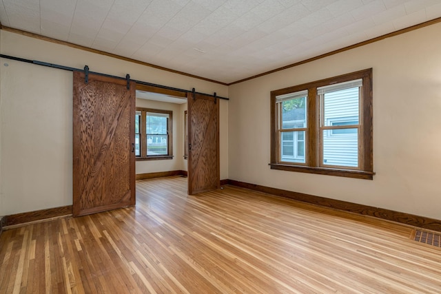 616 5th St, Mankato, MN 56001 - unfurnished room with a barn door, ornamental molding, and light wood-style floors