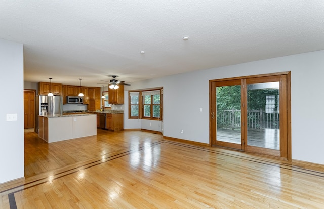 2319 Viola View Ln NE, Rochester, MN 55906 - unfurnished living room featuring light wood-type flooring, healthy amount of natural light, a ceiling fan, and a textured ceiling